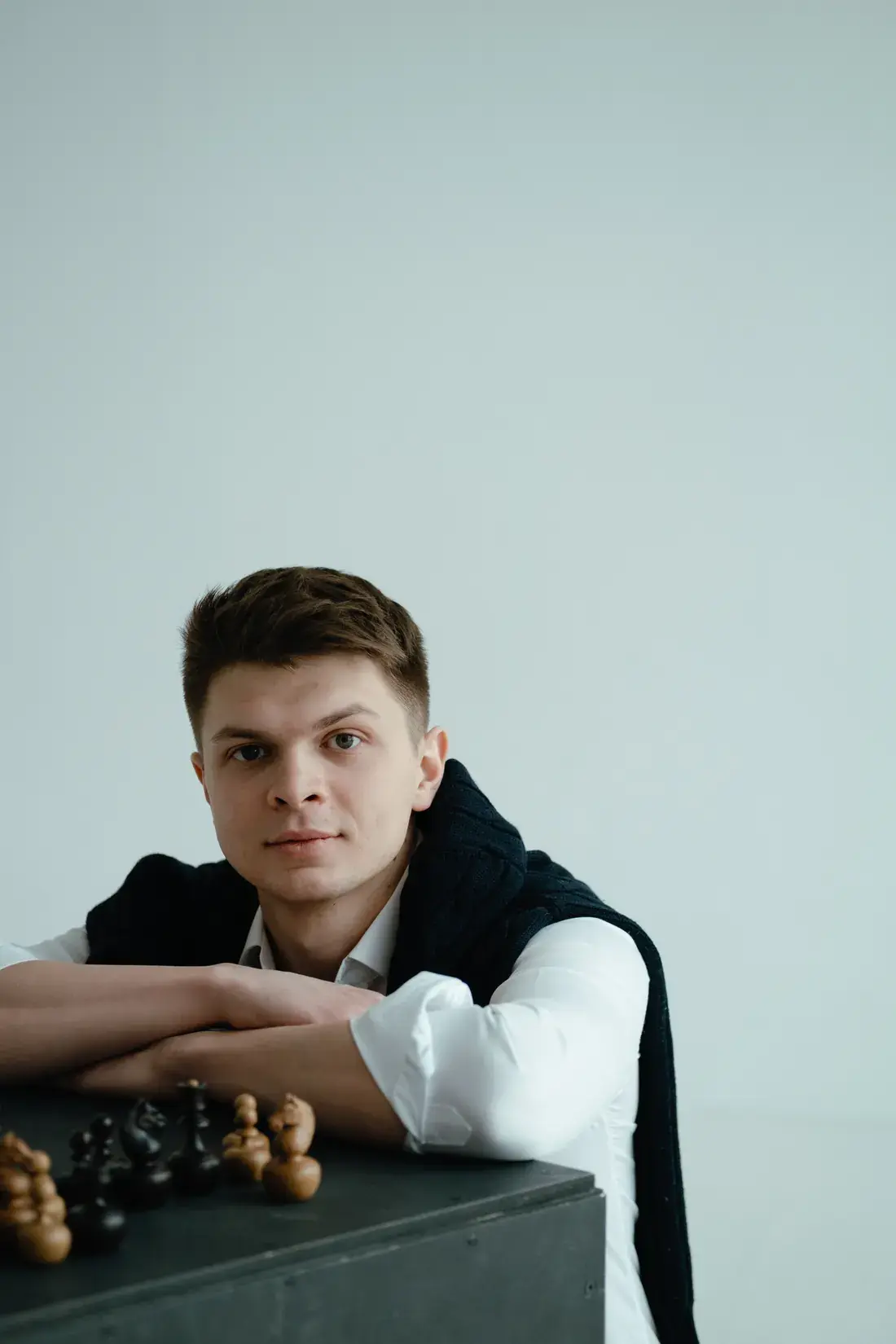 Константин Никологорский смотрит в камеру, перед ним шахматные фигуры
