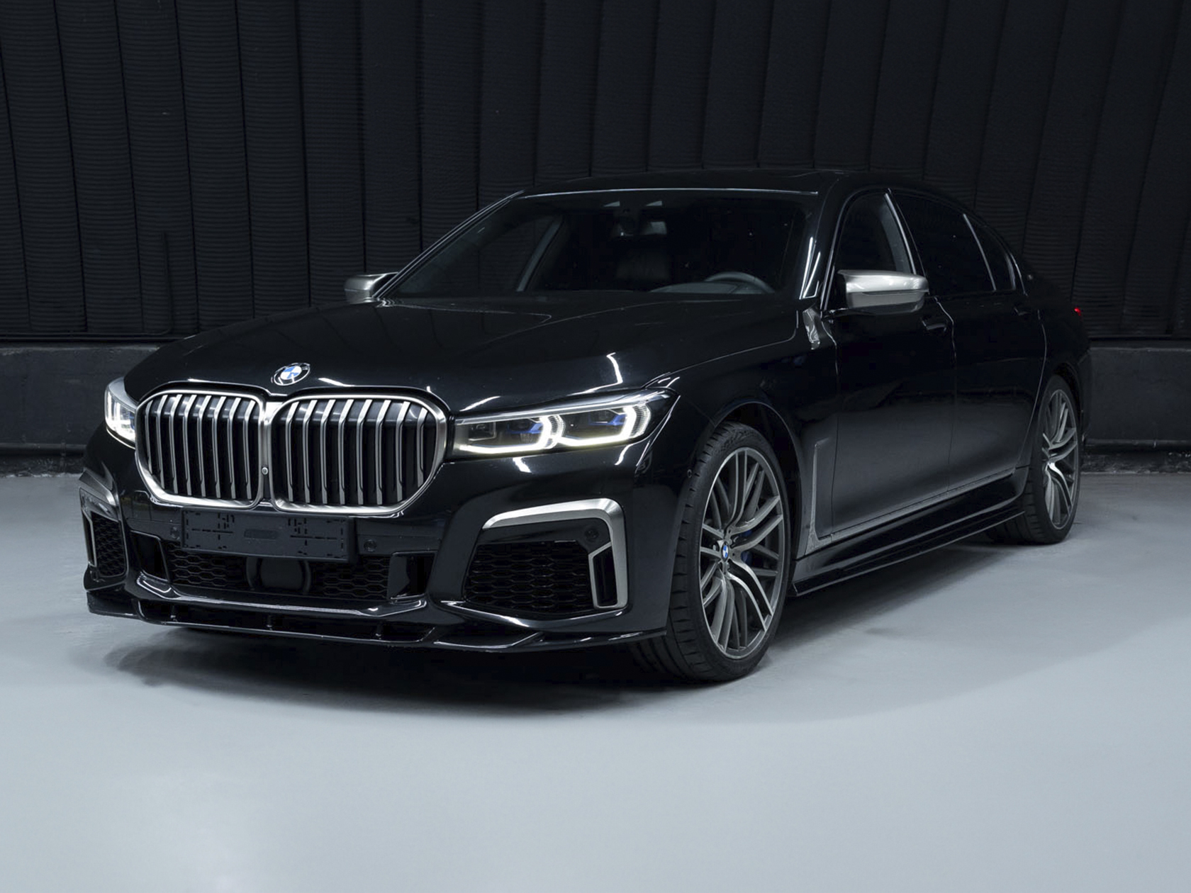 На данном изображении представлен автомобиль BMW 760 Li xDrive, воплощение роскоши и мощи. Этот флагманский седан BMW сочетает в себе изысканный дизайн и передовые технологии, обеспечивая высочайший уровень комфорта и производительности. Кузов автомобиля выполнен в стильных оттенках, придавая ему роскошный и элегантный вид. Динамичные линии, характерные для BMW, и эксклюзивные детали дизайна создают величественный облик, а легкосплавные диски колес дополняют общий внешний вид. Логотип BMW и эмблема 760 Li на капоте говорят о высоком статусе этой модели. Это изображение передает не только эстетику автомобиля, но и обещание роскоши и технического совершенства, которые предоставляет BMW 760 Li xDrive.