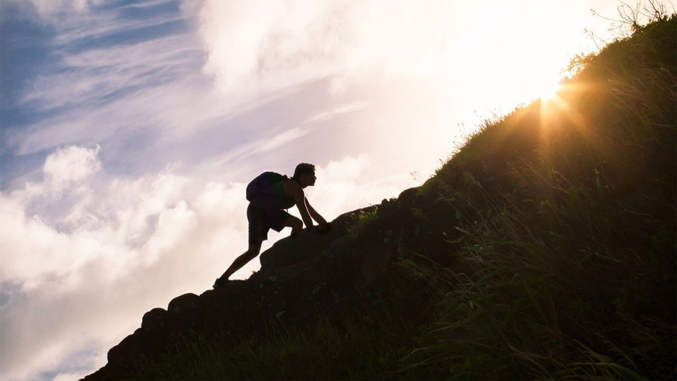a man climbing a mountain watching a sun rise