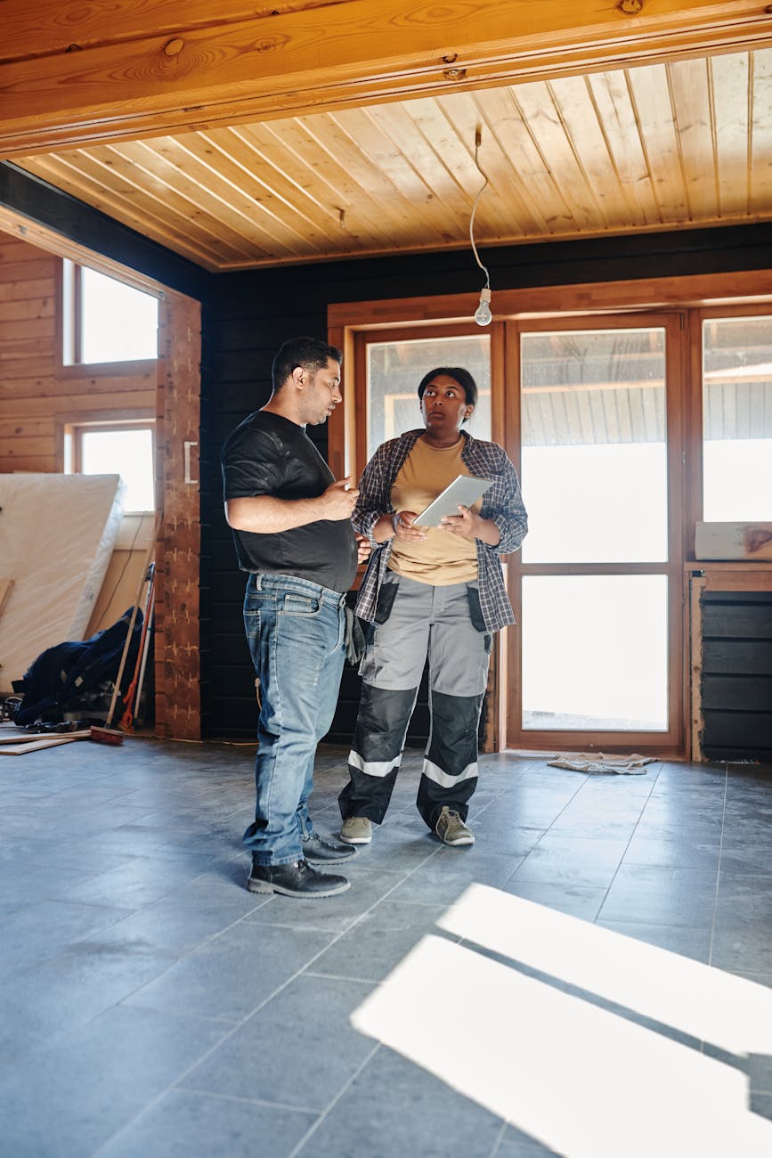 Two contractors discussing renovation plans indoors, showcasing teamwork.