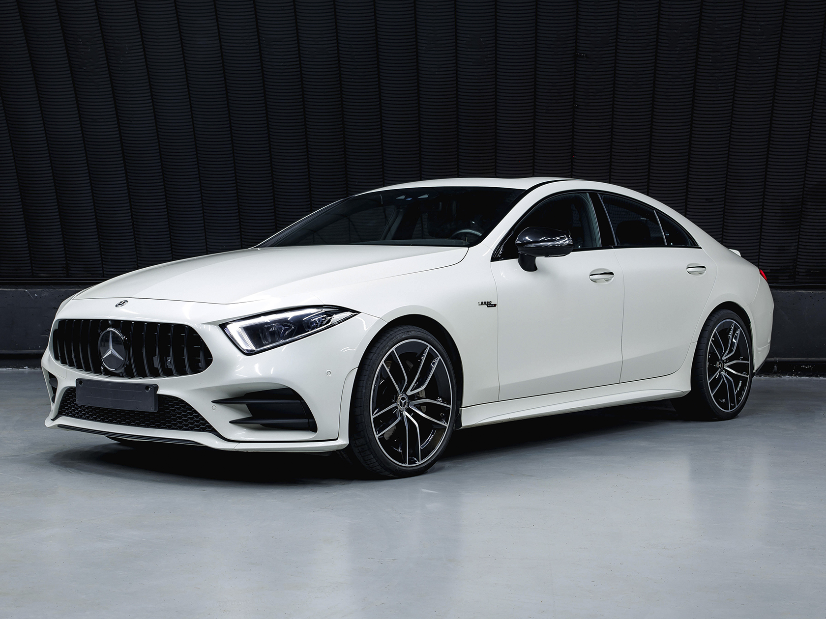 На данном изображении представлен автомобиль Mercedes-Benz CLS 53 AMG 4Matic+, эмблема роскоши и высокой производительности. Этот спортивный купе-седан сочетает в себе элегантный стиль и передовые технологии, обеспечивая водителю уникальный опыт вождения. Кузов автомобиля выполнен в изысканных оттенках, придавая ему динамичный и стильный вид. Характерные черты дизайна AMG, такие как динамичные линии и агрессивные детали передней части, подчеркивают спортивный характер CLS 53, а легкосплавные диски колес добавляют эксклюзивности. Логотип Mercedes-Benz и эмблема AMG на капоте говорят о высоком статусе и производительности этой модели. Это изображение передает не только внешний вид автомобиля, но и обещание роскоши и мощи, характерных для Mercedes-Benz CLS 53 AMG 4Matic+.