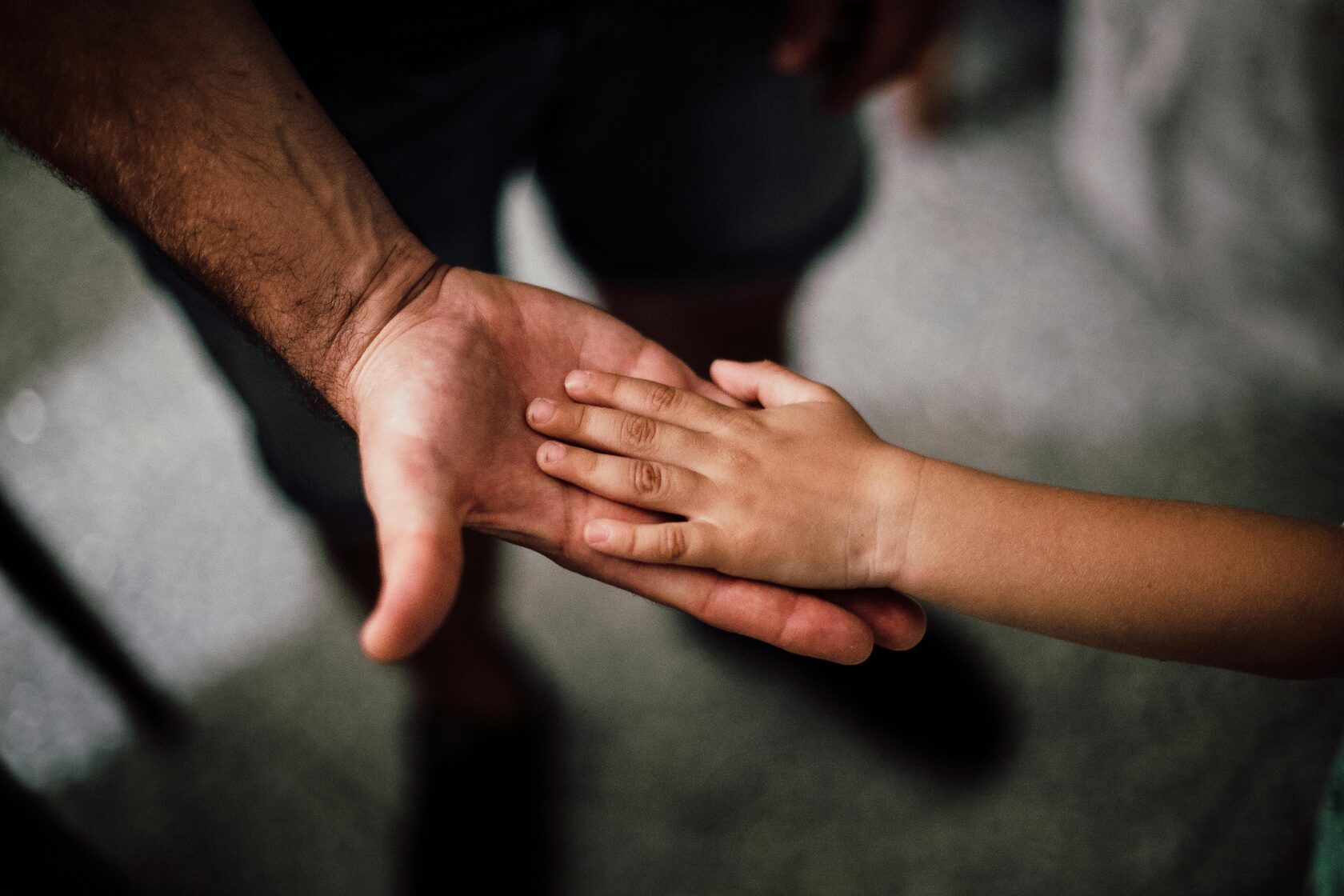 a hand of a grown-up with a hand of a small child on top